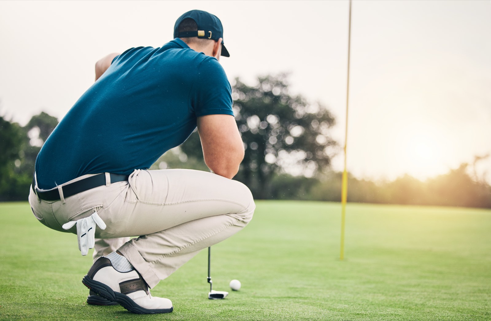 A golfer reading a putt at dusk